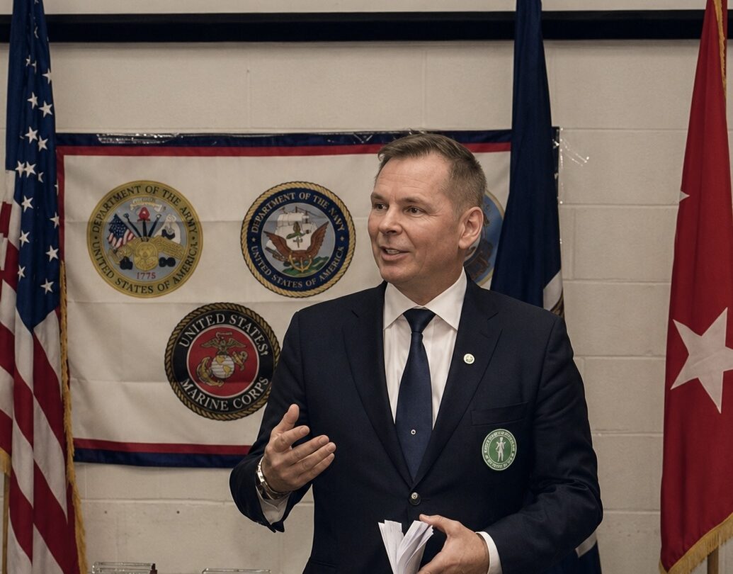 Dan-Viggo Bergtun holder foredrag i Washington foran amerikanske militære emblemer og flagg.